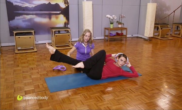 instructor with female student exercising on mat with smartbells